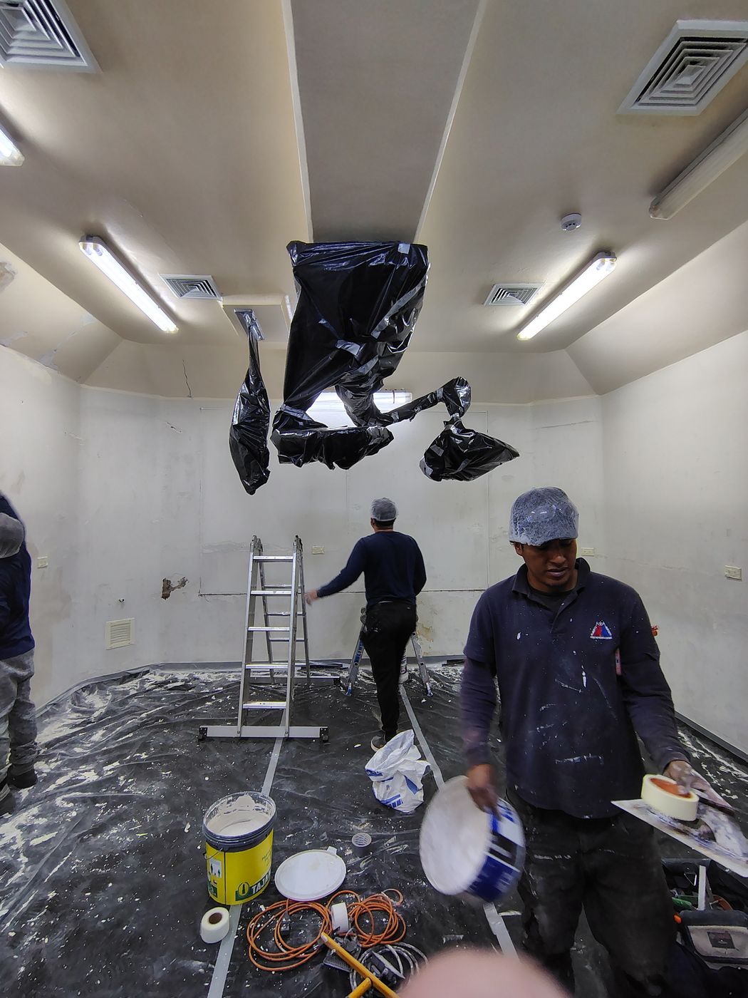 Personal preparando las superficies, con los equipos y el piso protegidos con plástico