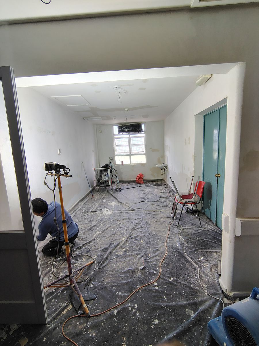 Personal reparando y emparejando las superficies de una sala, con el piso cubierto con plástico