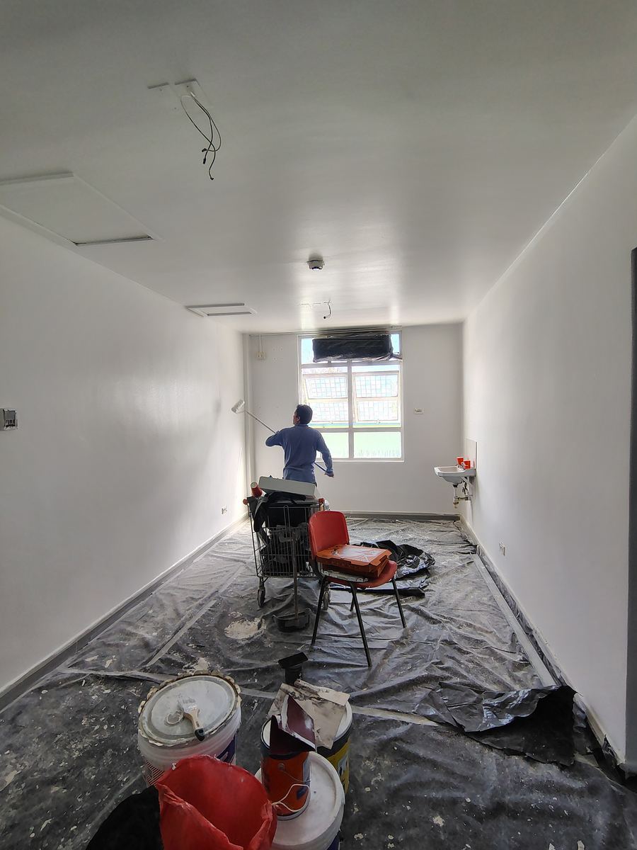 Pintura de muros con rodillo en una sala con el piso protegido