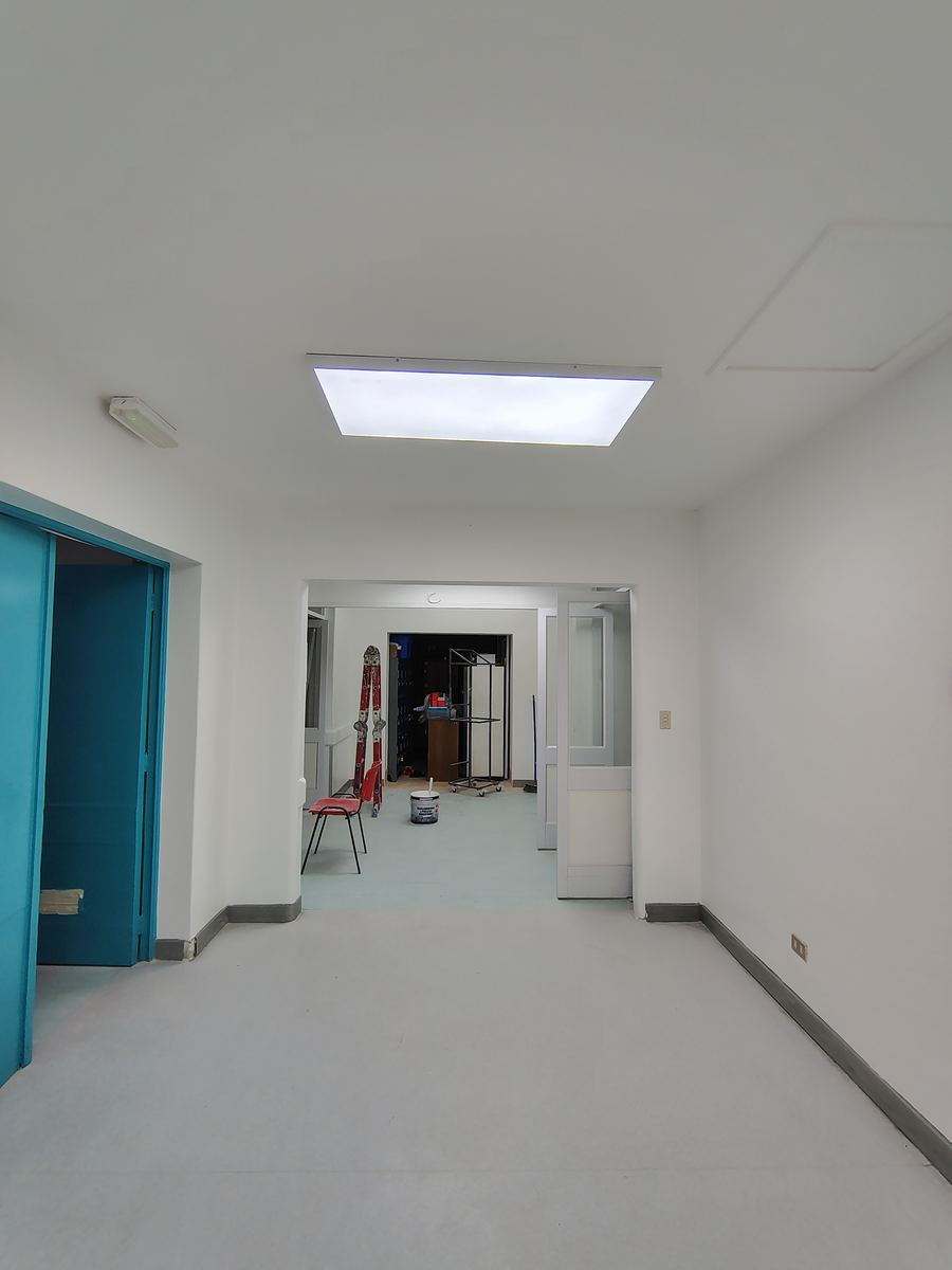 Sala terminada, con los muros y el cielo pintados de blanco y una puerta celeste